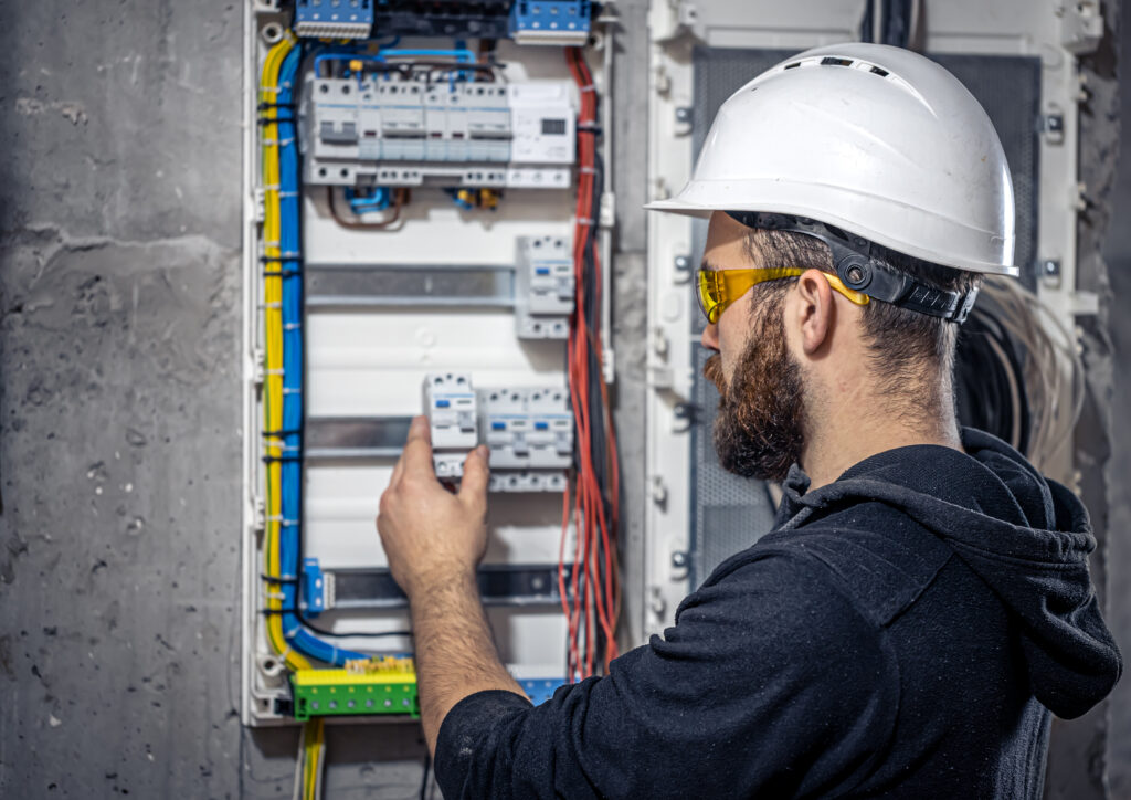 Eletricista instalando disjuntores no quadro elétrico.